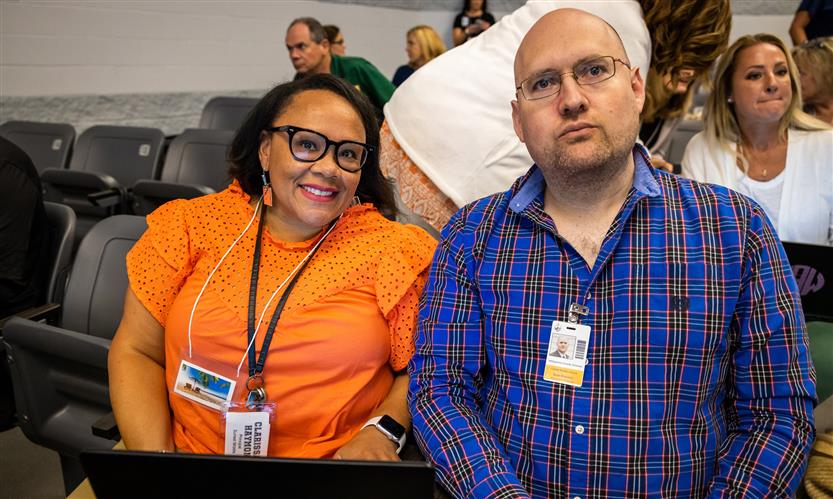 Two administrators sit in a theater and smile together